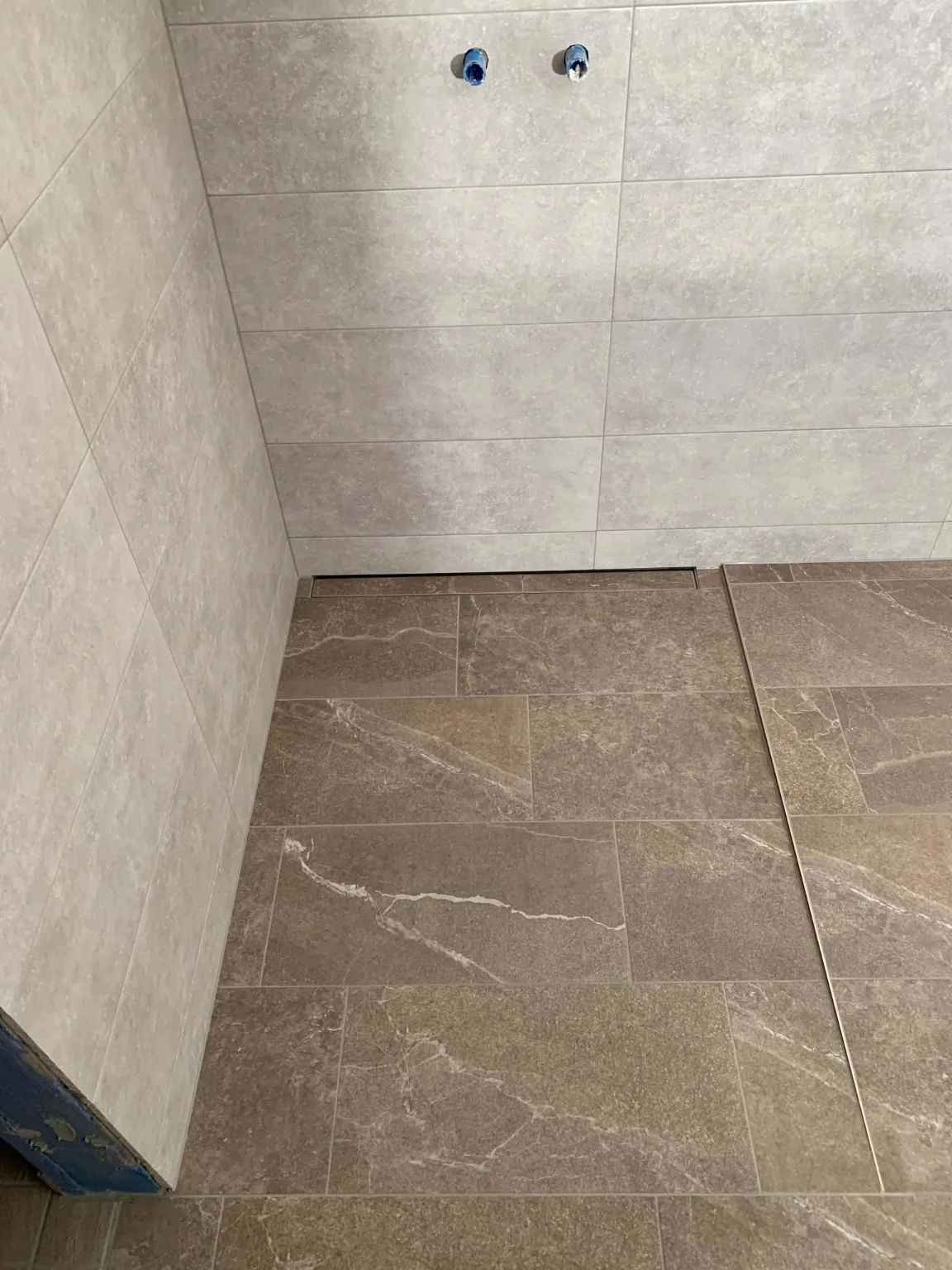 Real stone-effect floor with light wall tiles from our tiling work portfolio
